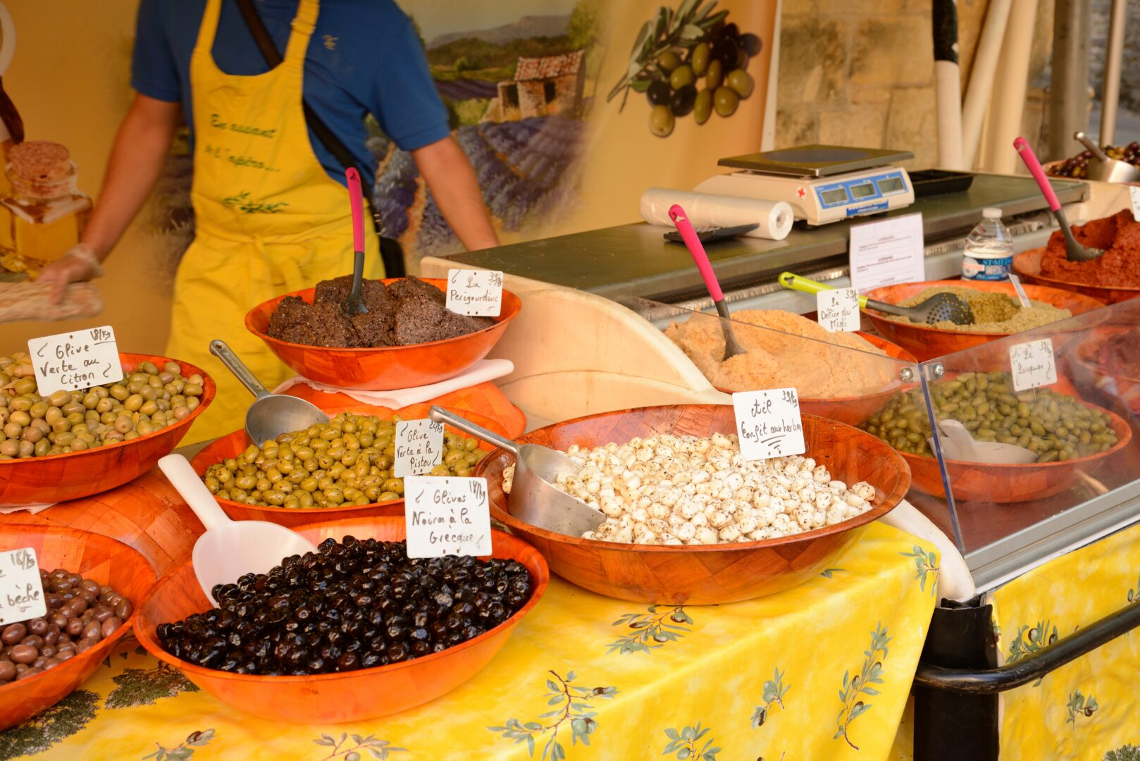Stand de marché proposant des olives et tapenades sur une nappe jaune dans la ville de Sarlat